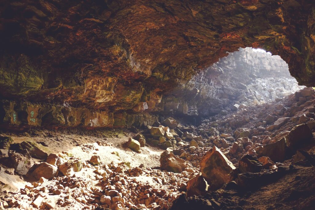 A brown rocky cave with light streaming in from the opening