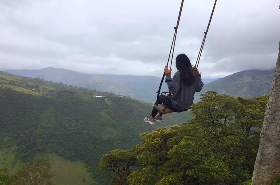 Brina, shown from behind, on a swing that overlooks lush hills and valleys.Lesser known underrated travel destinations to add to your itinerary solo female travel