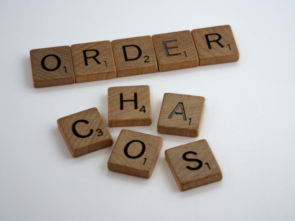 Order spelled out on top, chaos spelled out on bottom, both using scrabble pieces. Peace chaos indian writer author