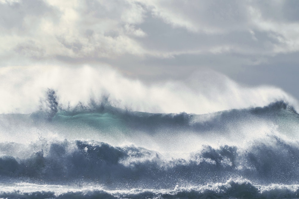 waves shown up close, under a cloudy sky.Peace chaos indian writer author