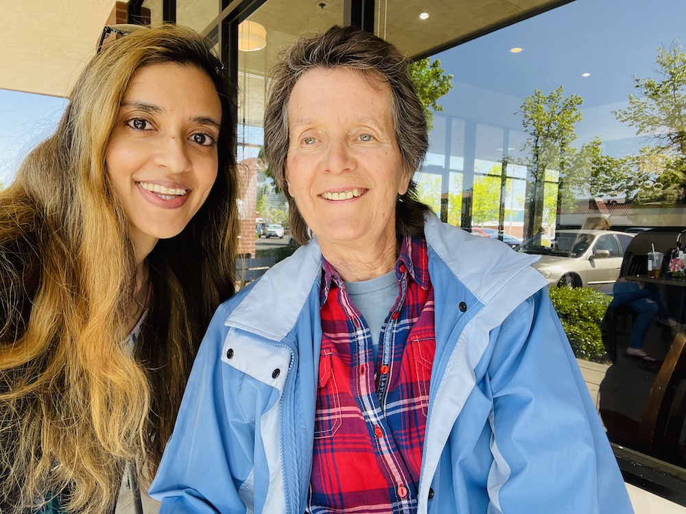 On the left, a woman with caramel hair smiles into the camera. On the right, a woman with short grey hair and a plaid shirt smiles into the camera.