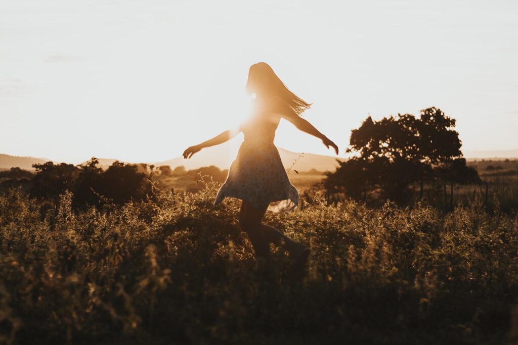 20 twenty things to do in your 20s twenties woman spinning in a field during sunset